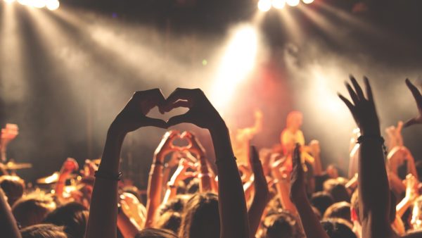 Festival crowd with hands raised at an outdoor bass music event