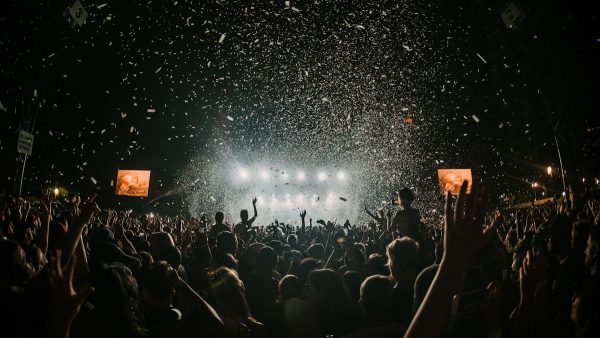 Large outdoor music festival with multiple stages and crowd at sunset